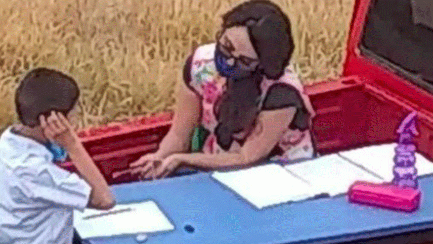 Una maestra da clases en la caja de una camioneta para mantener la distancia social
