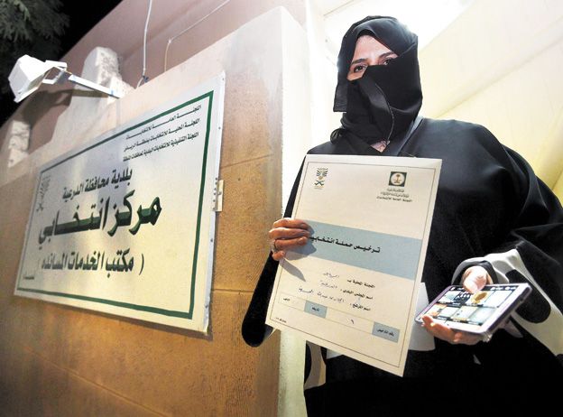 Participación. Una candidata al  concejo de Diriyah, en Riad, muestra una licencia de campaña electoral.