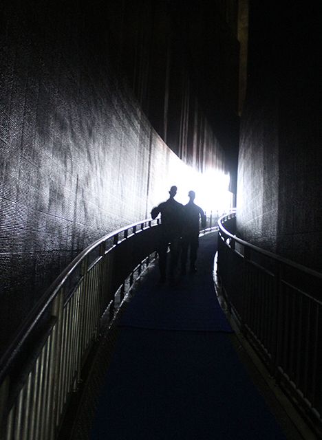 Un par de turistas en la entrada al museo que consiste en un corredor angosto y oscuro con agua descendiendo por las paredes que recrean el momento de la debacle.
