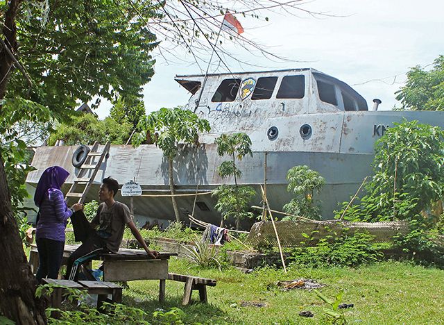 Dara Umarra y su novio hablan en el jardín de su casa donde dos botes encayaron durante el tsunami. Los visitantes también puede subir, pero el bote está ladeado en un ángulo muy empinado.