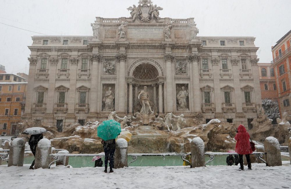 En la imagen, varias personas hacen fotografías a la Fontana di Trevi durante la nevada en Roma (Italia).