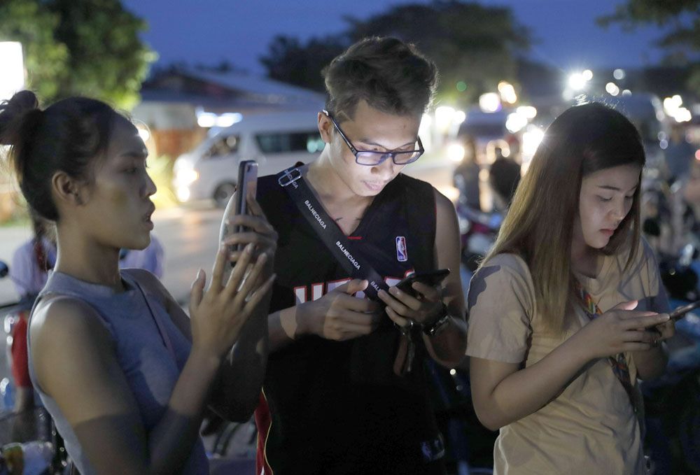 En Chiang Rai. La gente revisa sus teléfonos esperando noticias. Foto: AP.