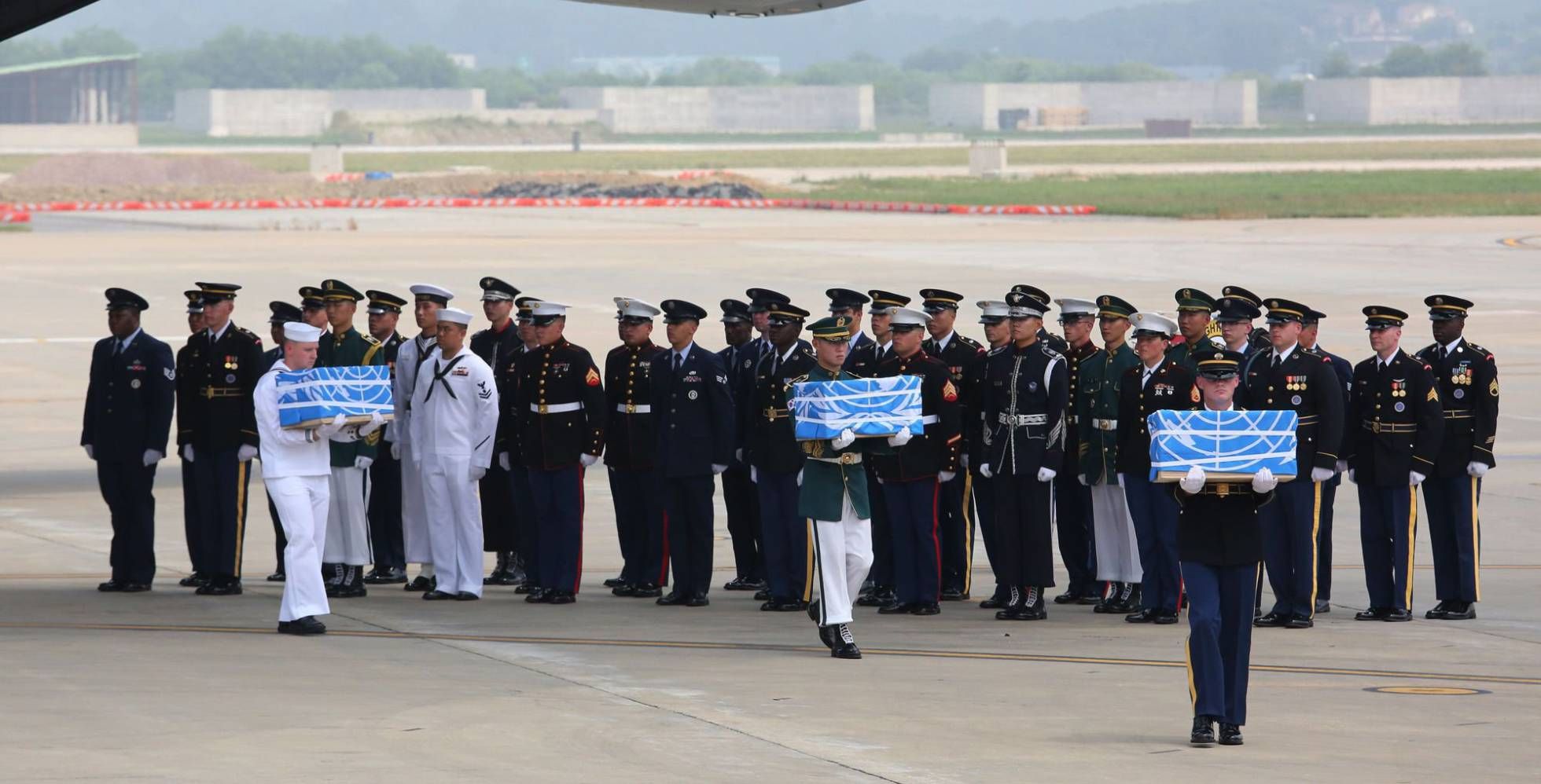 La guardia de honor de la ONU transporta las cajas con los restos procedentes de Corea del Norte (AFP)