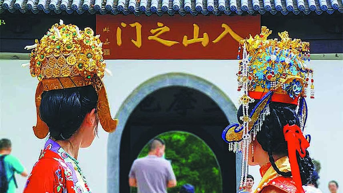 Dos mujeres con un atuendo tradicional chino lucen coronas hechas por Li Xin