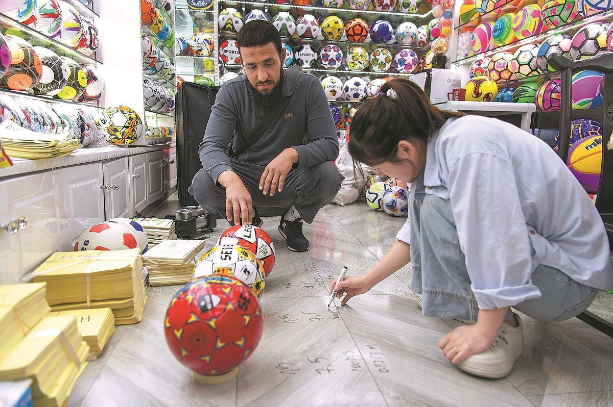 Una vendedora del Mercado de Comercio Internacional de Yiwu calcula el precio de unas pelotas de fútbol para un cliente extranjero. HU XIAOFEI / PARA CHINA DAILY