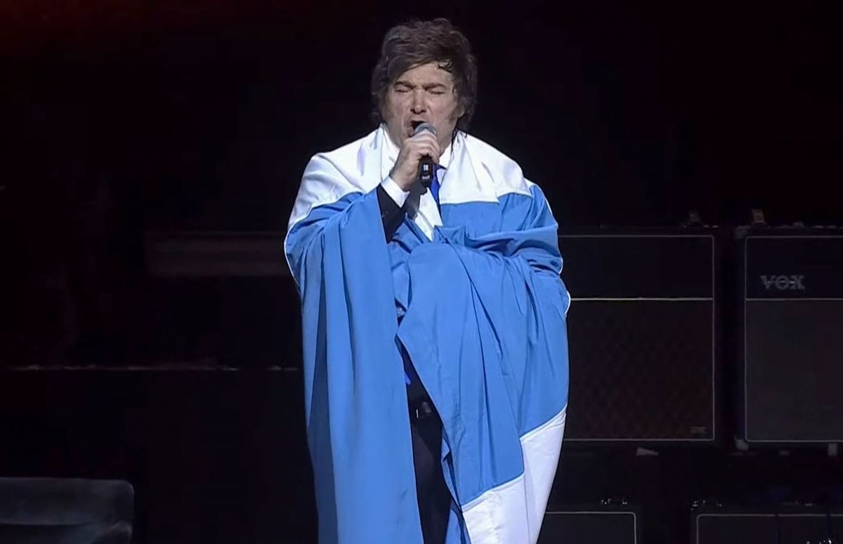 Milei cantando el himno, envuelto en la Bandera Argentina. Milei cantando el himno, envuelto en la Bandera Argentina.
