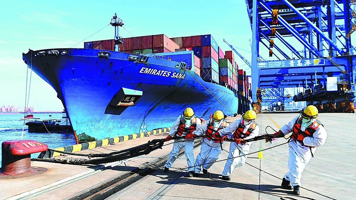 Unos operarios ayudan a amarrar un carguero en Qingdao
