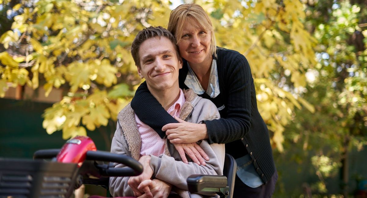 Martín Ferrer en la silla a motor que utiliza para desplazarse en trayectos largos. En la imagen lo acompaña su mamá Diana.