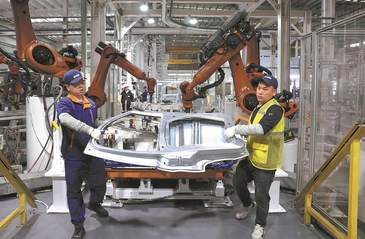 Los trabajadores transportan piezas de automóviles en la línea de producción de una fábrica en Fuzhou