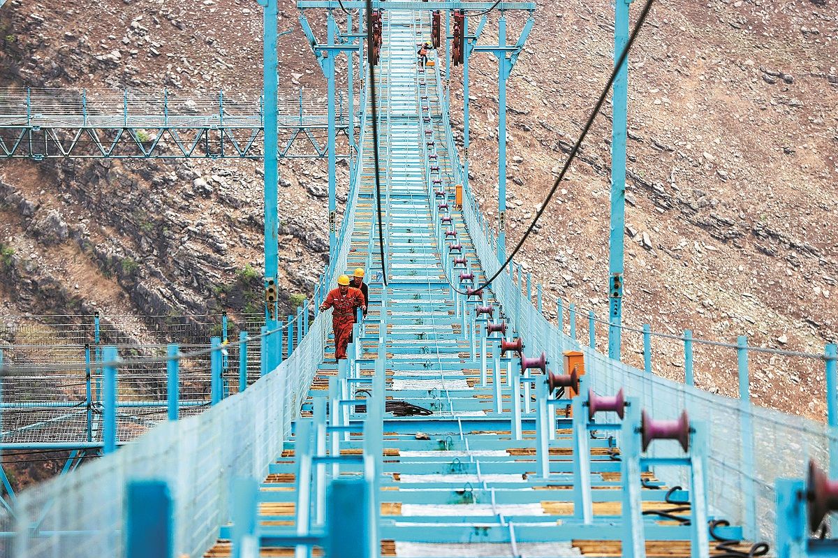 Los trabajadores utilizan una pasarela especial mientras construyen el puente sobre el río Zangke en la provincia de Guizhou. QU HONGLUN / SERVICIO DE NOTICIAS DE CHINA