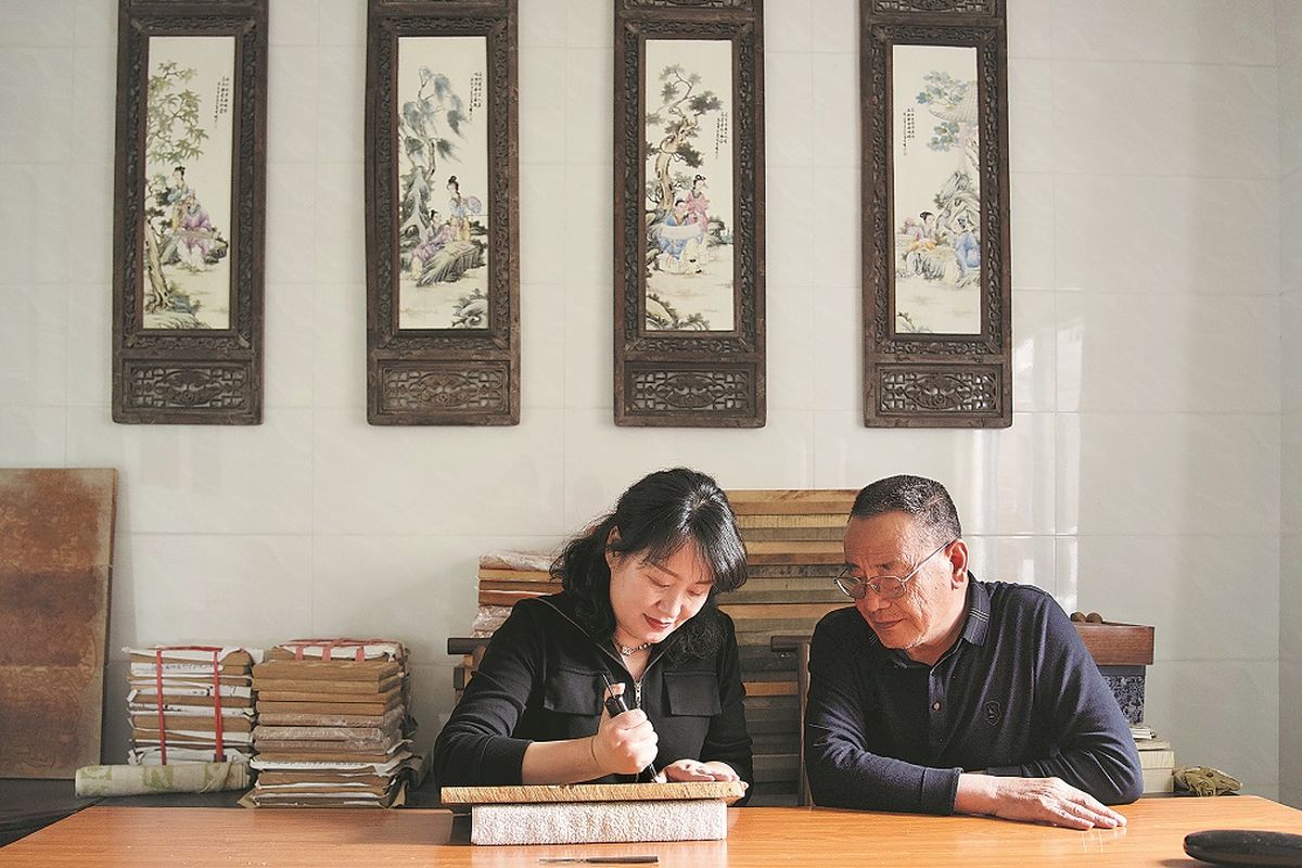 Chen Meiqi talla un bloque de madera con la guía de su padre, Chen Yishi. PARA USO DE CHINA DAILY .