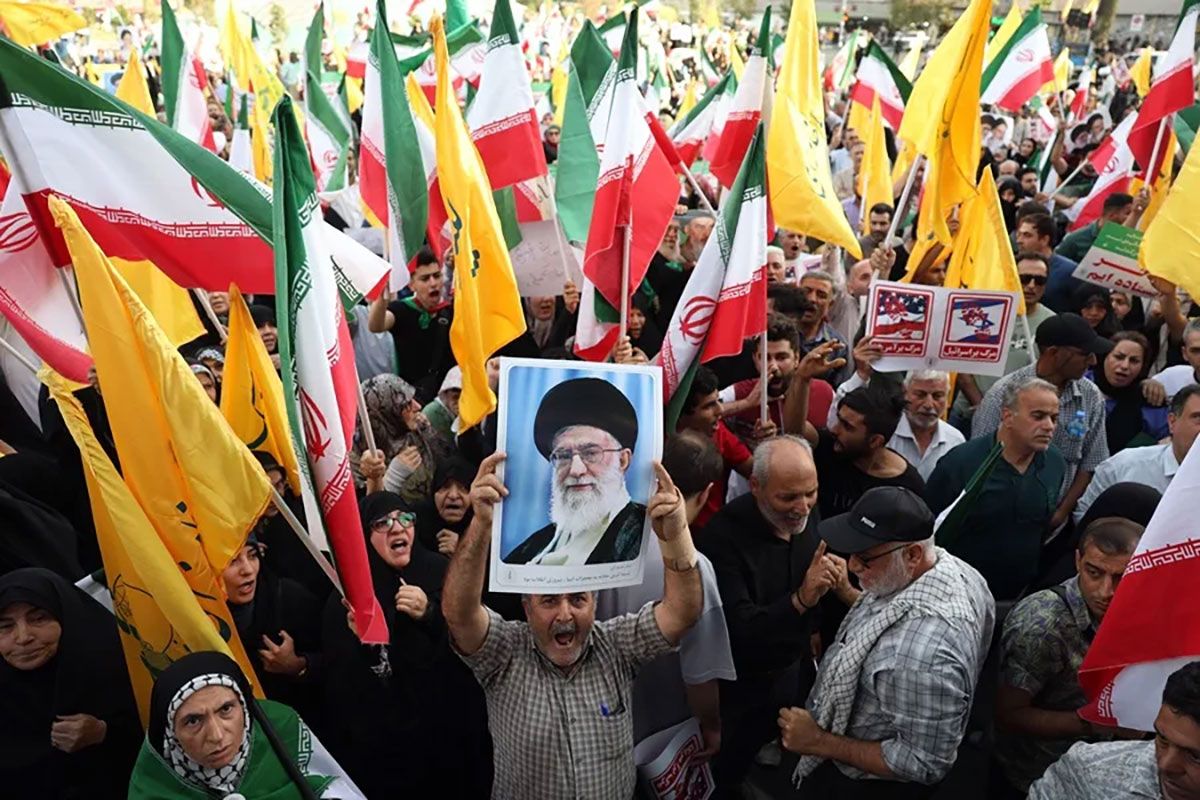 Un iraní sostiene un retrato del líder supremo iraní, el ayatolá Alí Jamenei, entre banderas nacionales de Irán durante una manifestación en Teherán tras el alto el fuego con Israel. Crédito: EFE/Abedin Taherkenareh.