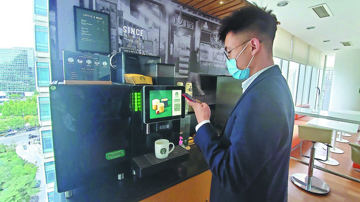 Un empleado compra café en una máquina expendedora dentro de su lugar de trabajo en Beijing. PARA USO DE CHINA DAILY