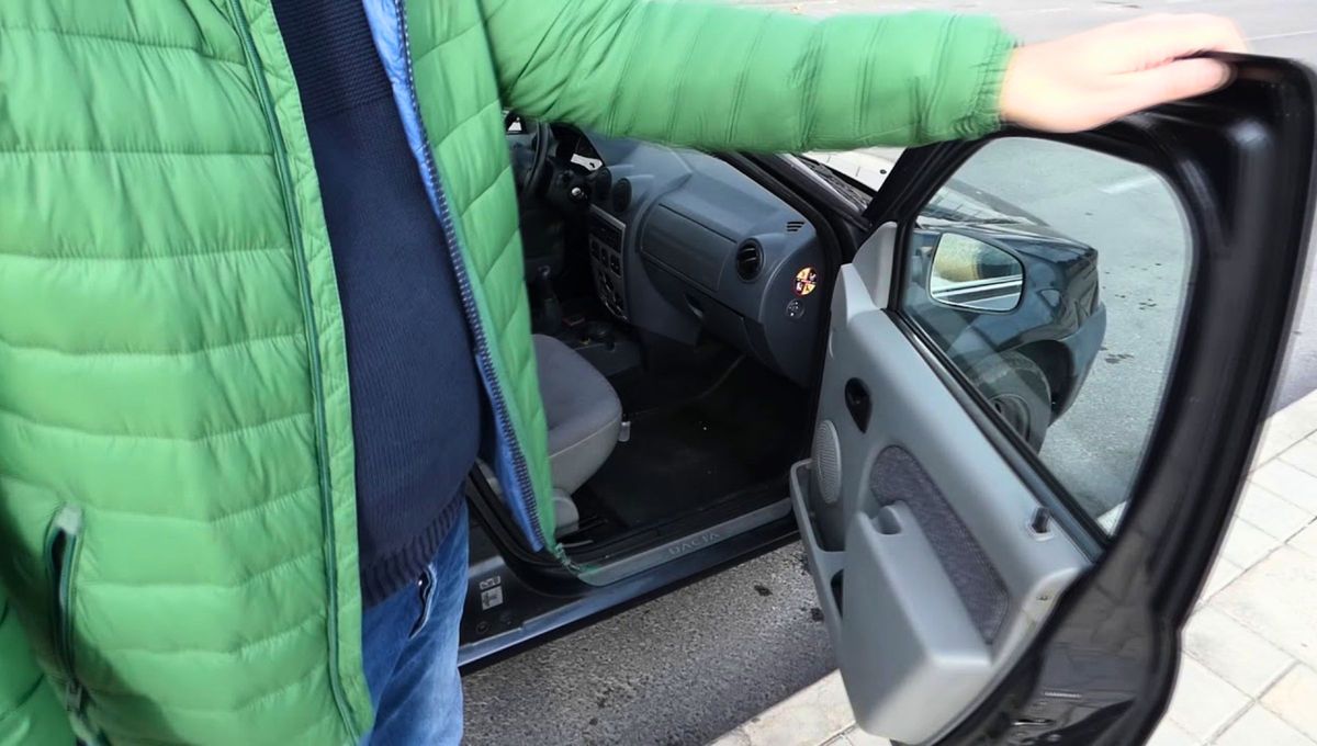 Un conductor observa detenidamente de dónde proviene el ruido de la puerta de su auto Un conductor observa detenidamente de dónde proviene el ruido de la puerta de su auto