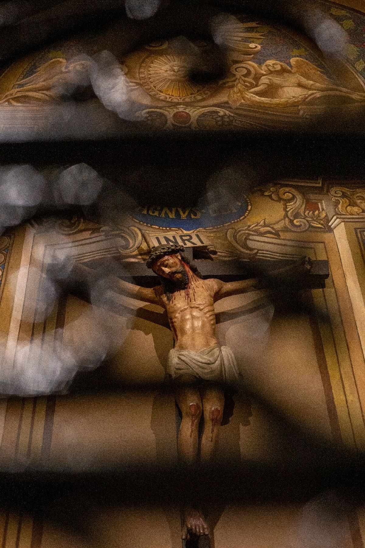 El cuerpo del sacrificio: Jesús crucificado, enmarcado por hierro. La sangre es símbolo, pero también historia. La redención se mira desde la herida.