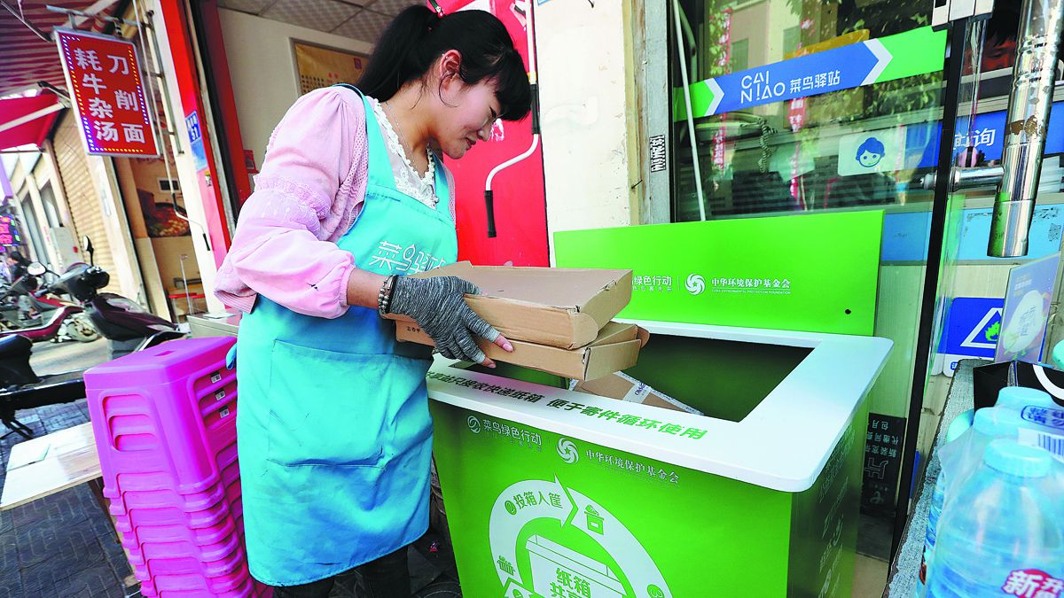 Una mujer arroja cajas de entrega vacías en un contenedor de reciclaje en una comunidad en Kunming