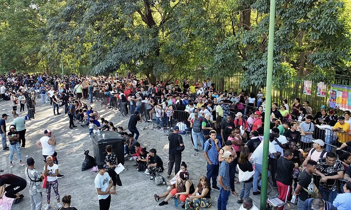 Migrantes en fila en una estación migratoria