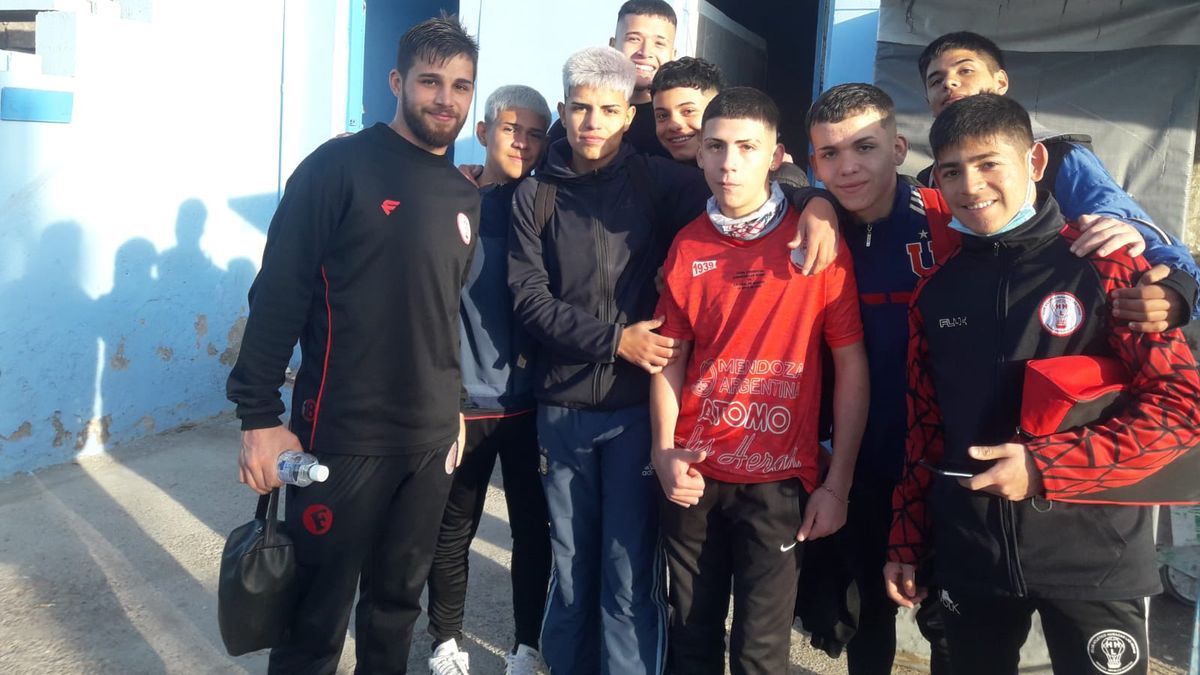 Javier Peñaloza posa con los hinhas de Huracán Las Heras en la canncha de Gutiérrez.