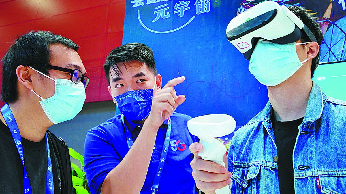 Un visitante (derecha) prueba los juegos del metaverso en una feria en Guangzhou