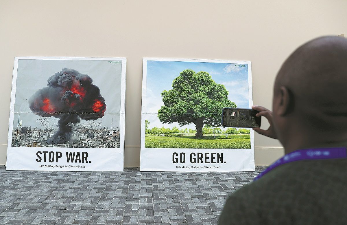 Un hombre toma una fotografía de los carteles expuestos para la COP28 en Dubái, Emiratos Árabes Unidos. WANG ZHENDONG / XINHUA