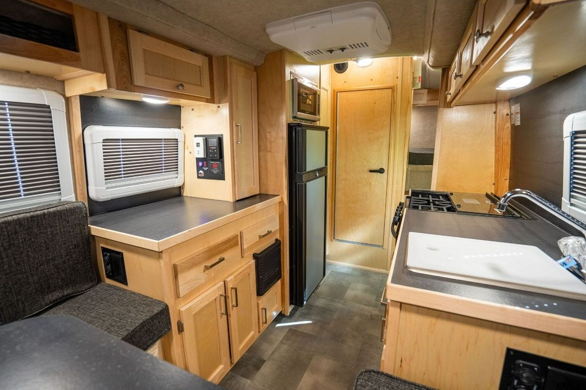 El interior del Scamp 19 Deluxe, como se muestra en la imagen, es un testimonio de cómo se puede lograr el lujo y la funcionalidad en un espacio compacto. Los acabados en madera de abedul o roble aportan calidez y elegancia, mientras que la inteligente distribución maximiza cada centímetro para ofrecer una experiencia de campamento superior. Desde la cocina completamente equipada con estufa, refrigerador y microondas, hasta el cómodo comedor que se convierte en cama, y el baño con ducha, esta casa rodante está diseñada para el confort. El interior del Scamp 19 Deluxe, como se muestra en la imagen, es un testimonio de cómo se puede lograr el lujo y la funcionalidad en un espacio compacto. Los acabados en madera de abedul o roble aportan calidez y elegancia, mientras que la inteligente distribución maximiza cada centímetro para ofrecer una experiencia de campamento superior. Desde la cocina completamente equipada con estufa, refrigerador y microondas, hasta el cómodo comedor que se convierte en cama, y el baño con ducha, esta casa rodante está diseñada para el confort.