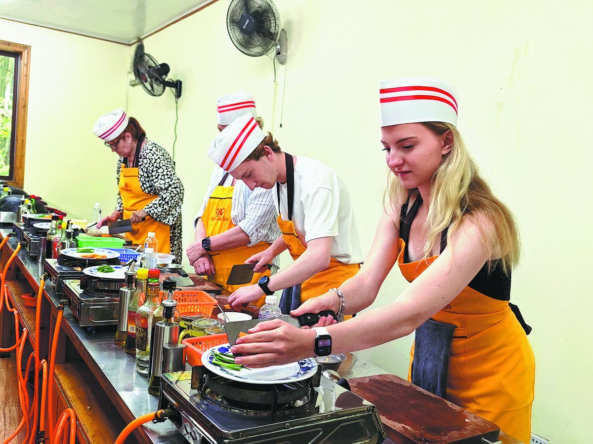 Visitantes extranjeros aprenden a preparar platos chinos en Yangshuo, región autónoma de la etnia zhuang de Guangxi. PARA USO DE CHINA DAILY.