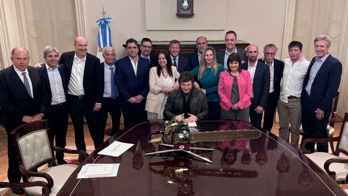 Javier Milei junto a gran parte de su gabinete y una motosierra en la mesa.