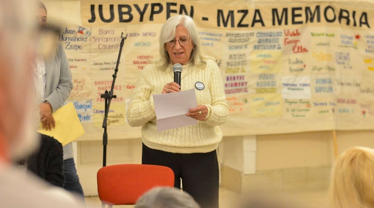 Una de las mjueres bordadoras -Ana María Villafañe- tomó la palabra. Detrás, una de las banderas bordadas con nombres de los desaparecidos de Mendoza.