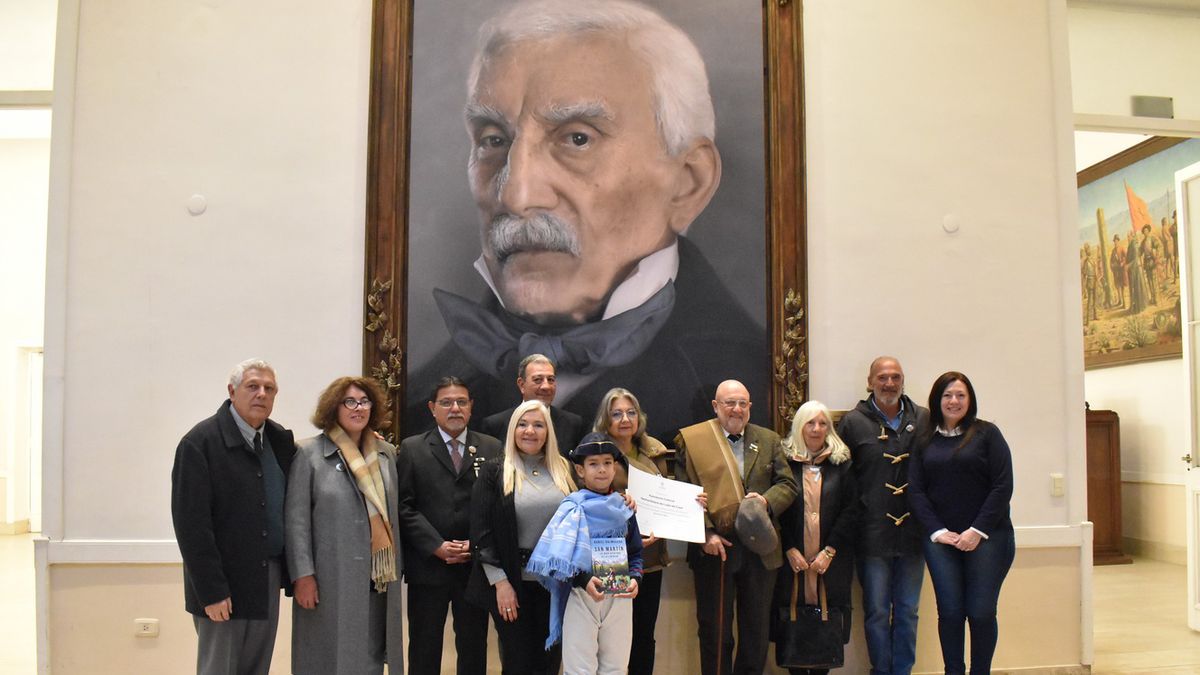 Integrantes de la Asociación Cultural Sanmartiniana de Luján posan junto al retrato del general San Martín en la Legislatura.
