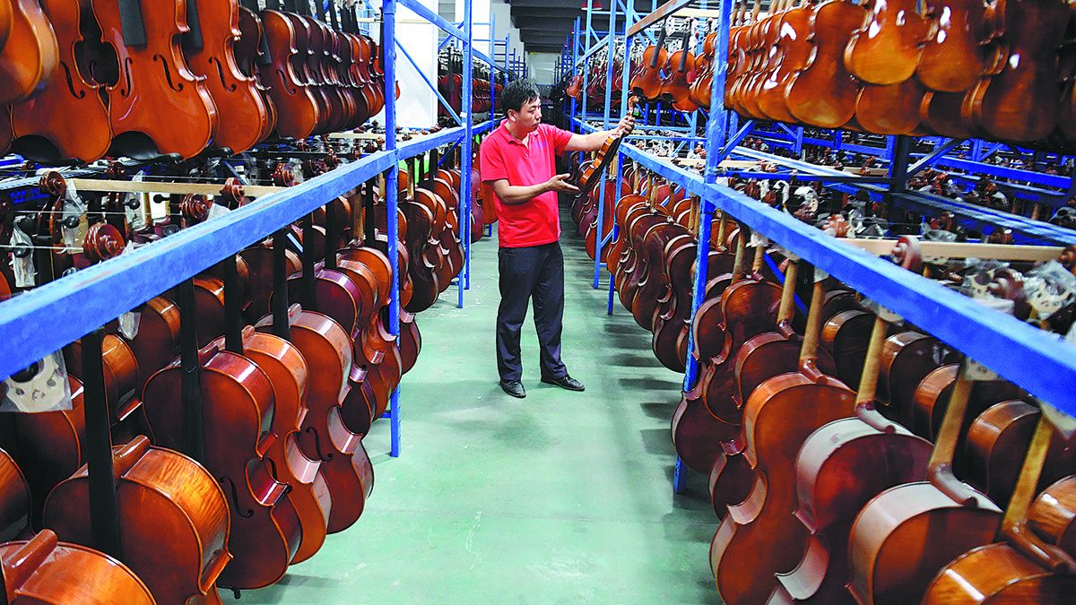 Un empleado comprueba la calidad de violines y violonchelos en una fábrica en el condado de Queshan, provincia de Henan. LI JIANAN / XINHUA