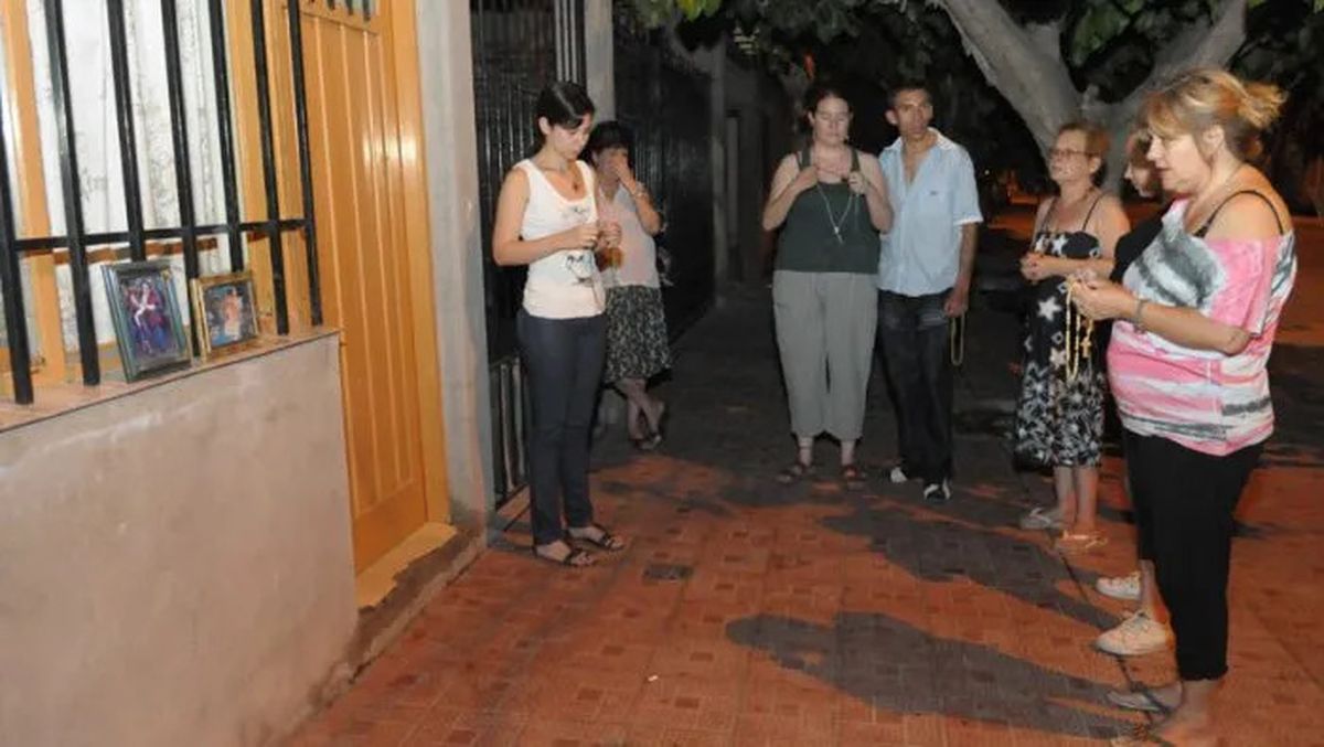 Vecinos en la puerta de la casa de la familia asesinada por un chico de 13 años, en Las Heras, en 2011.