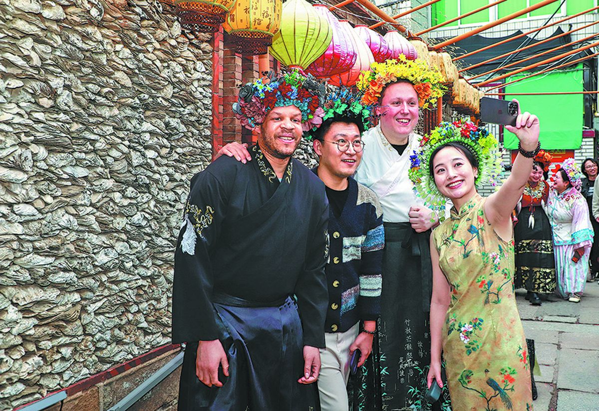 Visitantes adornados con tocados florales posan frente a una vivienda de conchas de ostión en la antigua aldea pesquera de Xunpu, Quanzhou, provincia de Fujian. CHEN YI / PARA CHINA DAILY.