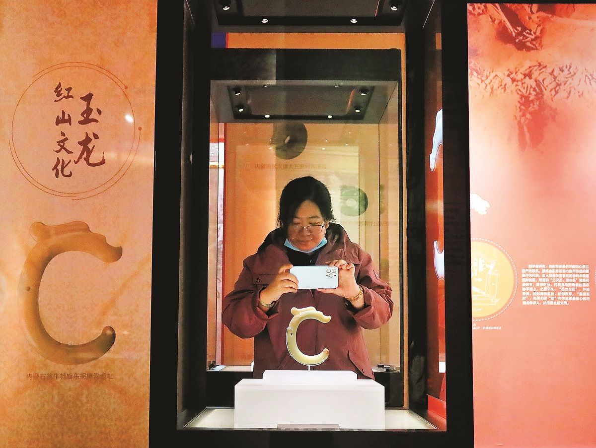 Un dragón de jade en forma de C en exhibición llama la atención de una visitante. JIANG DONG / CHINA DAILY.