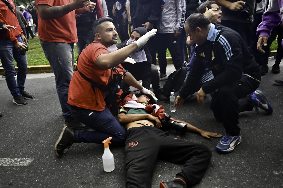 El fótagrago herido es asistido por manifestantes durante la marcha de Jubilados.