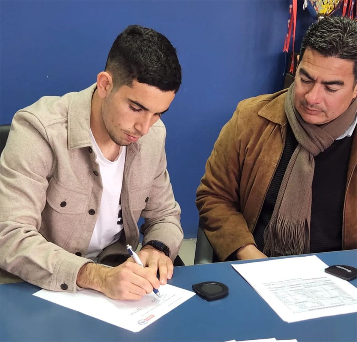 Lautaro Pastrán firma su primer contrato con Everton de Chile. Lo acompaña Fernando Malara.