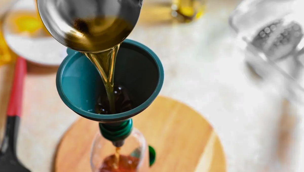 Persona coloca el aceite ya usado en una botella para reciclarlo Persona coloca el aceite ya usado en una botella para reciclarlo