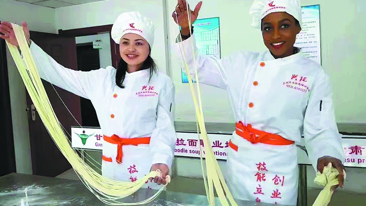 Visitantes de países participantes en la Iniciativa de la Franja y la Ruta aprenden cómo hacer los fideos con carne de Lanzhou en una escuela de capacitación en la provincia de Gansu. PARA USO DE CHINA DAILY 