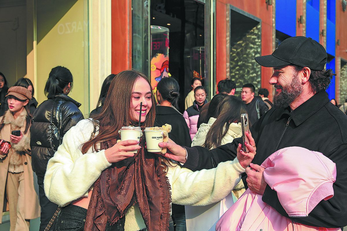 Una visitante extranjera posa con tazas de café decoradas con osos peludos en la cafetería 13DE MARZO de Shanghai. PARA USO DE CHINA DAILY.