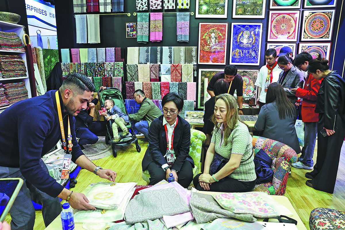 Un expositor pakistaní muestra a los visitantes sus bufandas de cachemira en la VIII Exposición Internacional de Importaciones de China en Shanghai.