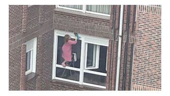 Una mujer se juega la vida para limpiar las ventanas de su departamento