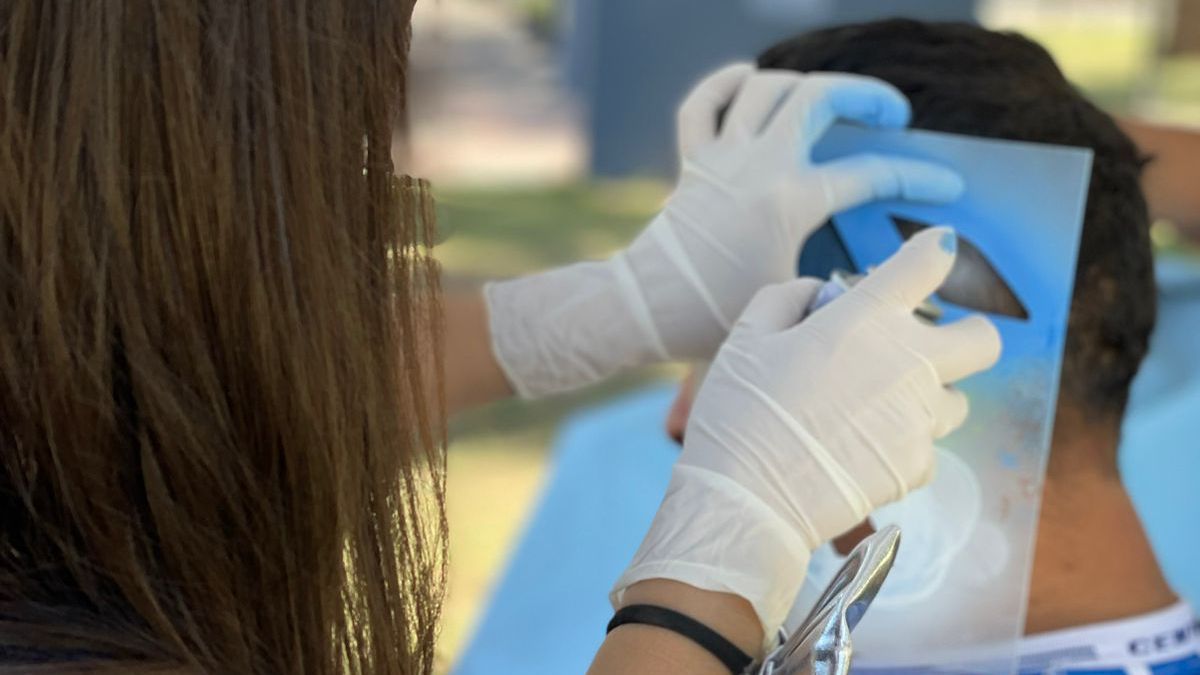 Mica aplicando la pintura especial tras el corte de pelo a los pequeños hinchas tunuyaninos de la selección argentina.