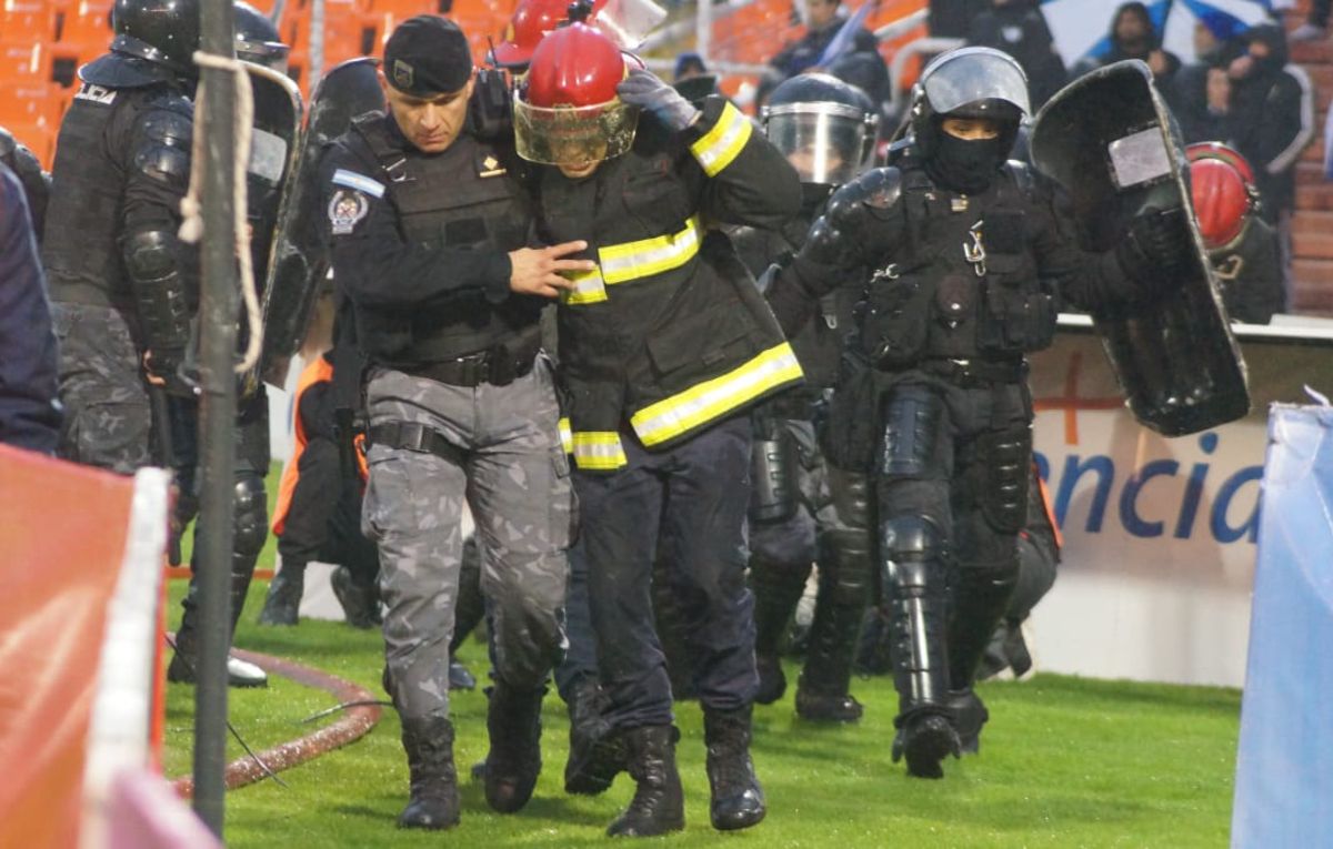 Bomberos y policías se cubren de los elementos que arrojan los hinchas de Godoy Cruz