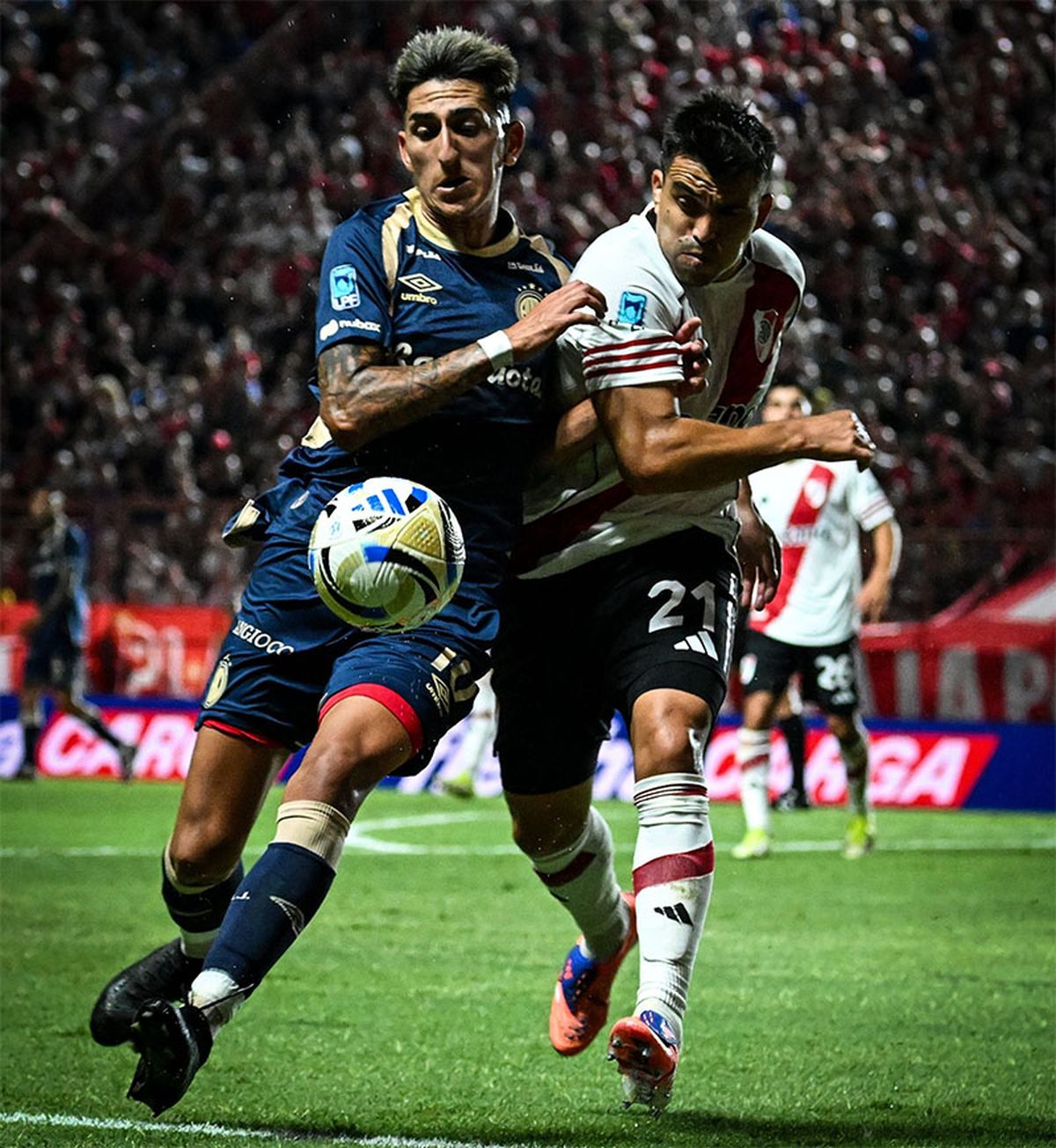 El defensor de River Marcos Acuña forcejea con Alan Lescano, el volante de Argentinos.