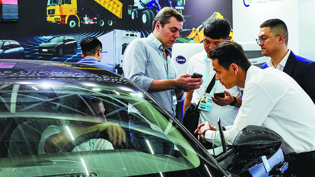 Visitantes preguntan sobre vehículos de nueva energía en un stand en la 133ª Feria de Cantón en Guangzhou, provincia de Guangdong. LIU DAWEI / XINHUA