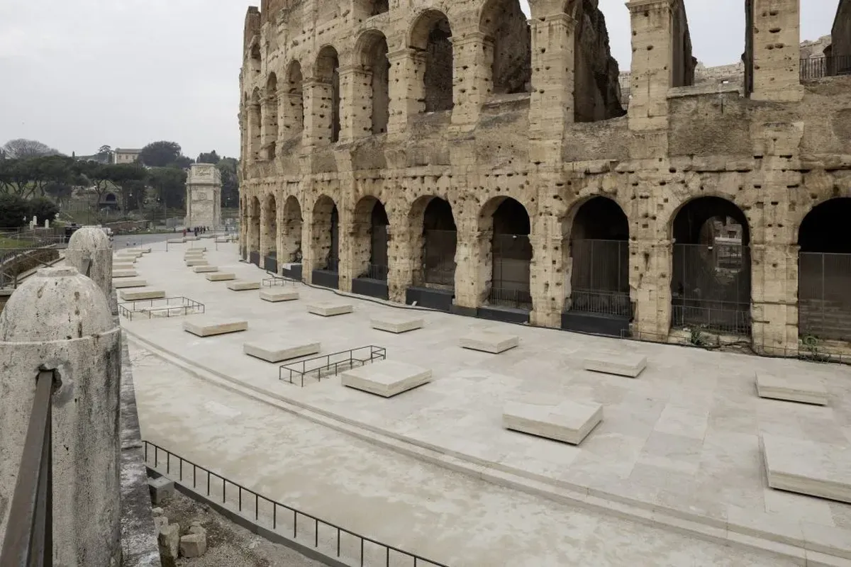 Vista panorámica de la zona peatonal sur del Coliseo tras su restauración, donde se han instalado bloques de travertino que evocan las antiguas columnas y permiten sentarse a los visitantes. Al fondo, se aprecia el Arco de Constantino. Vista panorámica de la zona peatonal sur del Coliseo tras su restauración, donde se han instalado bloques de travertino que evocan las antiguas columnas y permiten sentarse a los visitantes. Al fondo, se aprecia el Arco de Constantino.