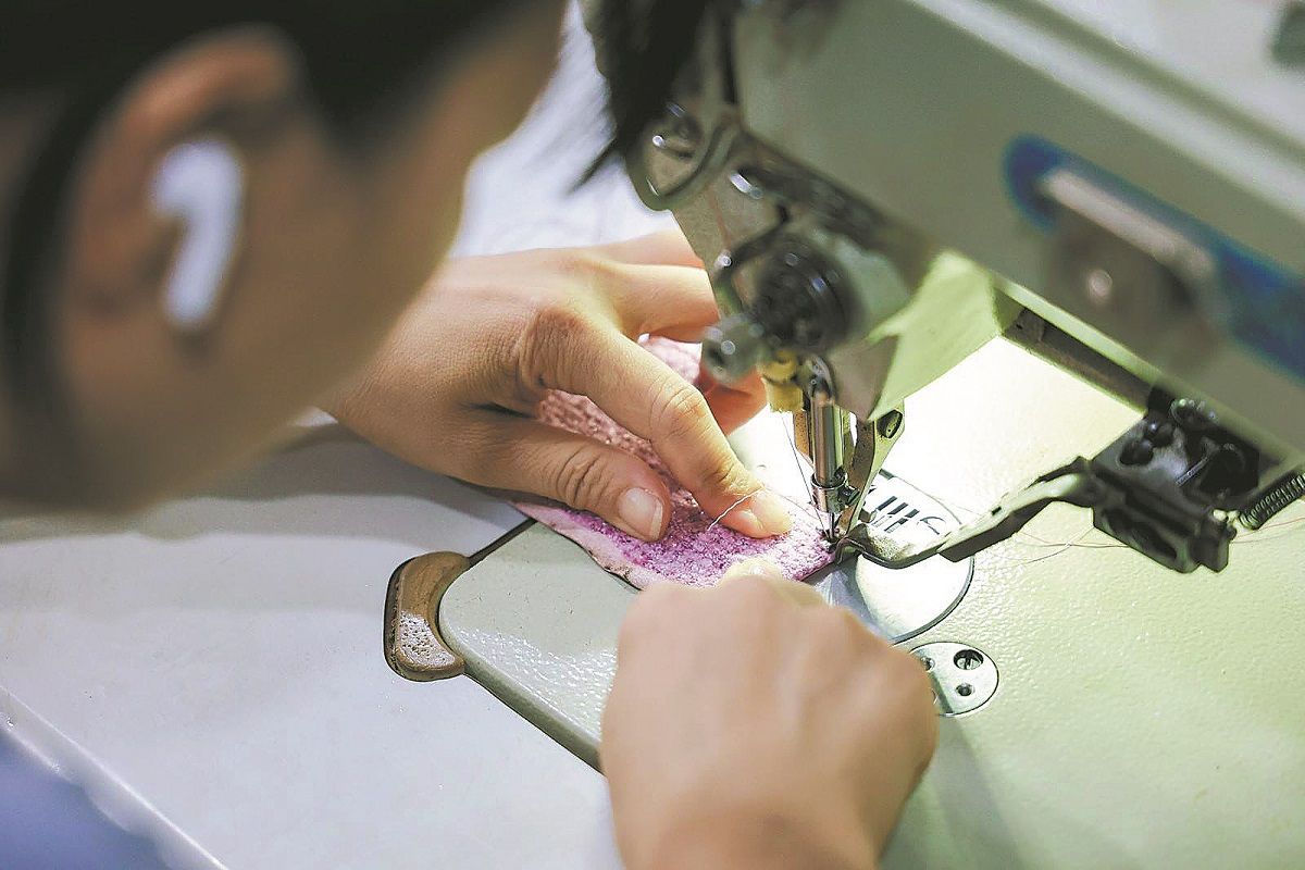 Una empleada fabrica una funda para móvil en un taller en Guangzhou, provincia de Guangdong. PARA USO DE CHINA DAILY.