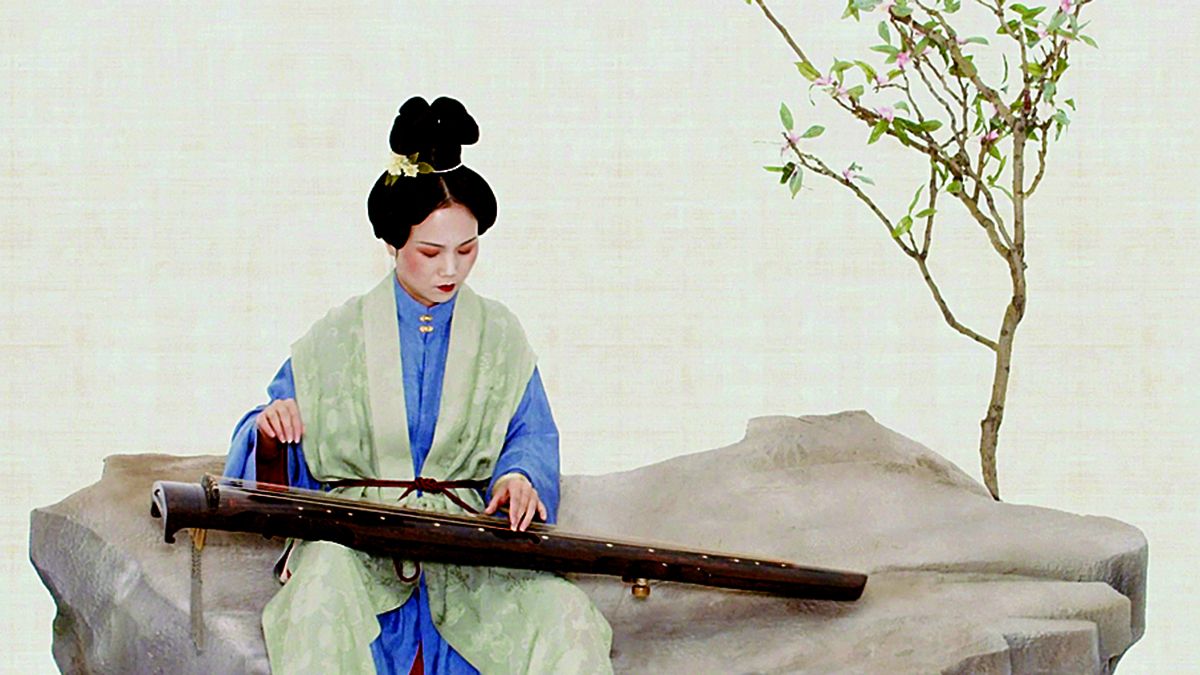 Una de los componentes de Zide Guqin Studio, vestida con atuendo tradicional, interpreta el guqin. PARA USO DE CHINA DAILY