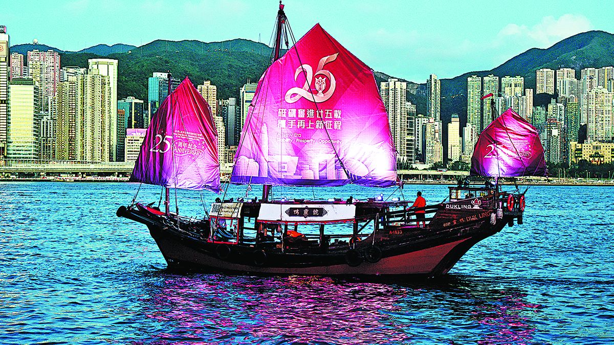 Un velero con pancartas que celebran el 25º aniversario del retorno de Hong Kong a la patria navega por el puerto de Victoria