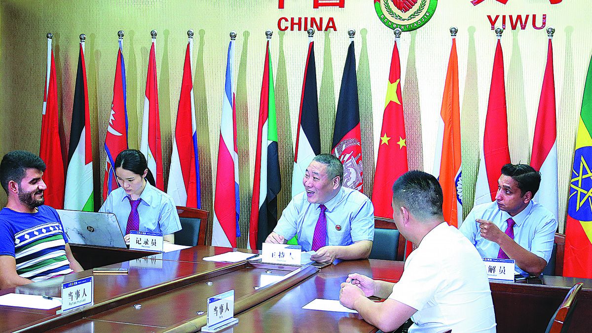 El director del equipo de mediación, Chen Yanjin (en el centro), ayuda a resolver un conflicto comercial en Yiwu, provincia de Zhejiang, junto con un voluntario nepalí (a la derecha). PARA USO DE CHINA DAILY&nbsp;