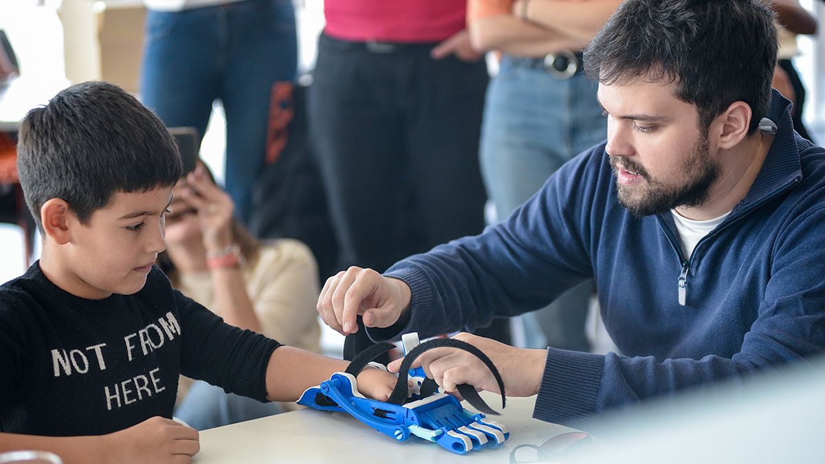 Gino Tubaro ayuda a un niño con la protesis 3D durante el Manotón de Banco Macro.